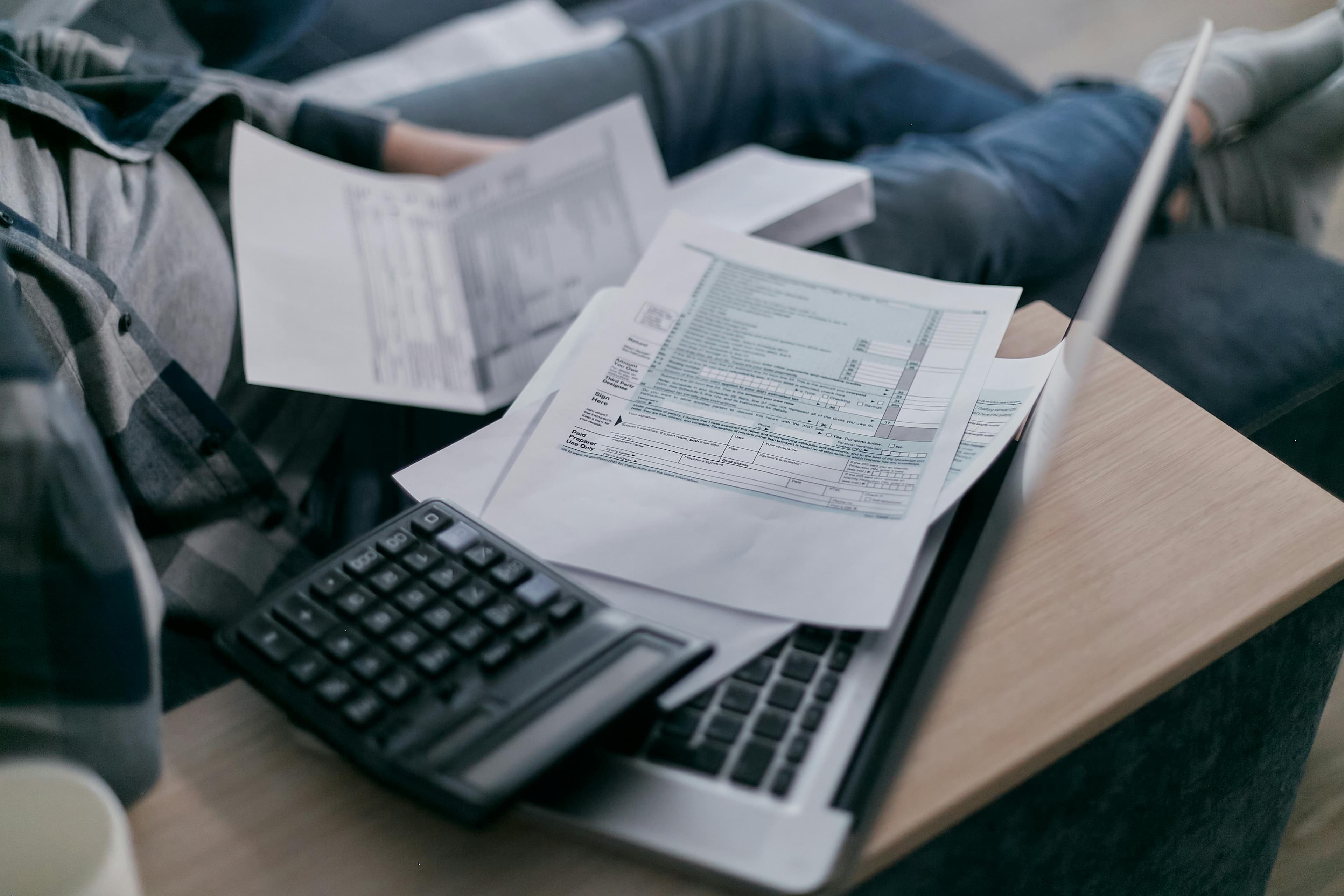 Person using laptop with documents for home buying